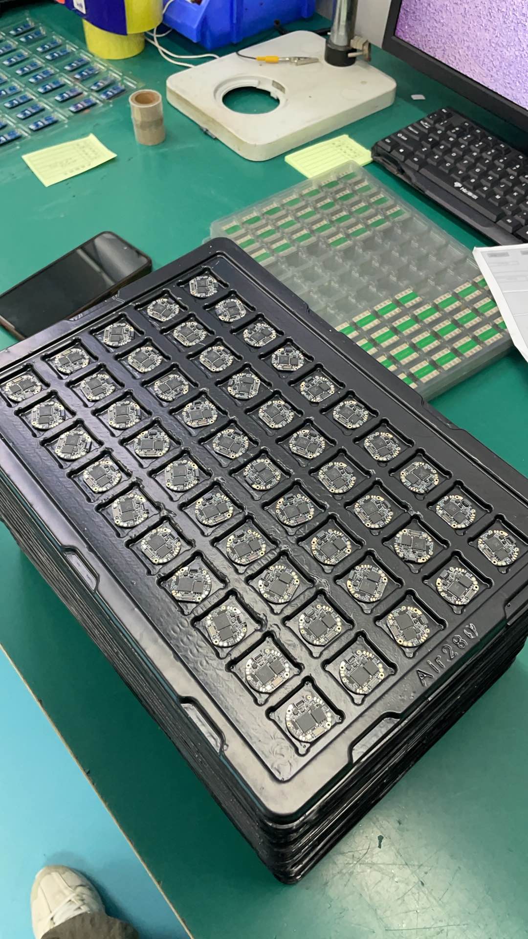 An electronics workbench with a microscope, keyboard and compact circuit-board assemblies.