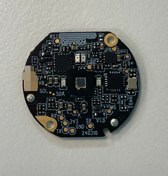 Close view of a round populated circuit board with components and gold-colored mounting holes.